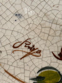 Close-up of a ceramic surface with a signature.